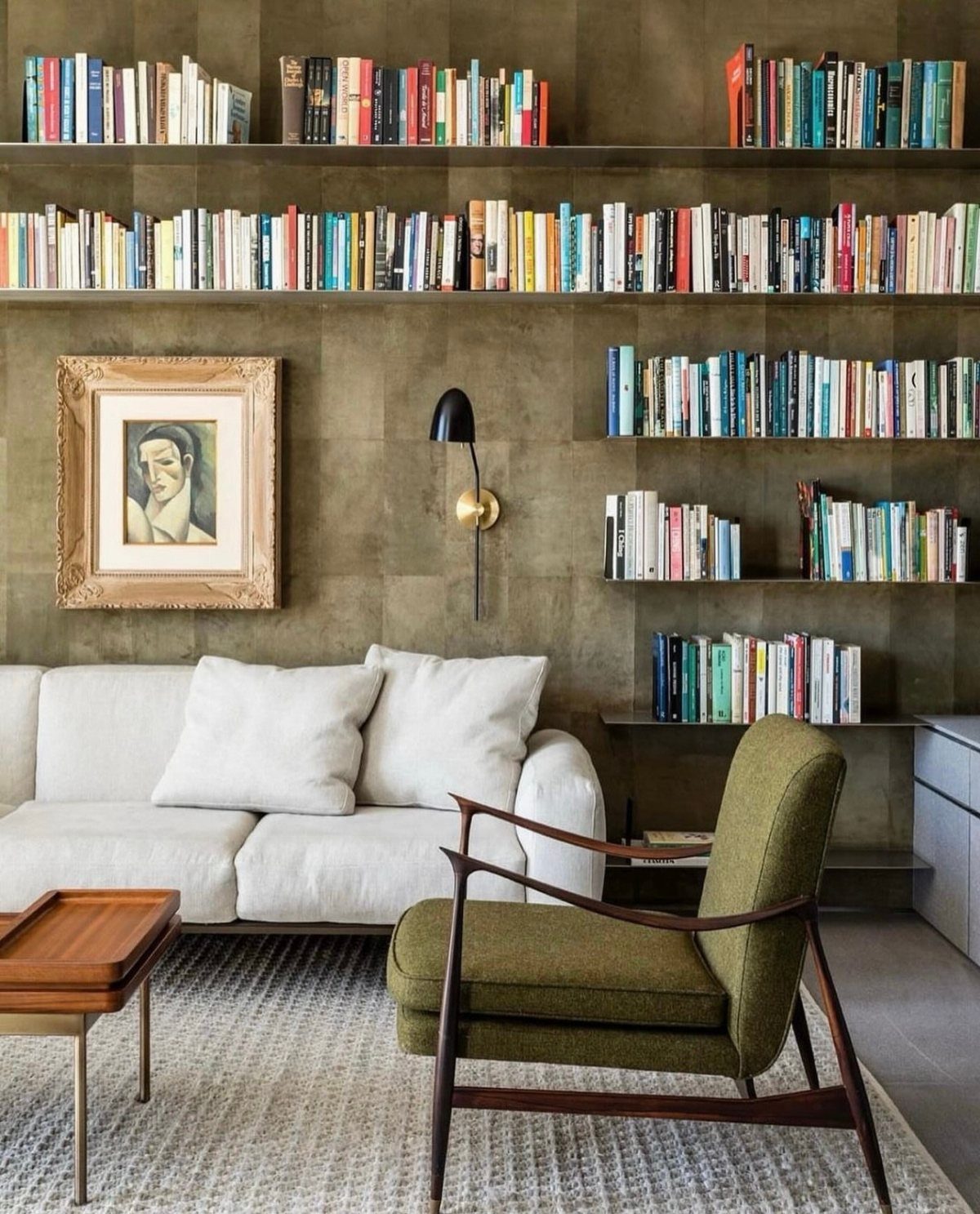 Modern minimalist floating shelves with books mounted on a brown wall above a sofa.