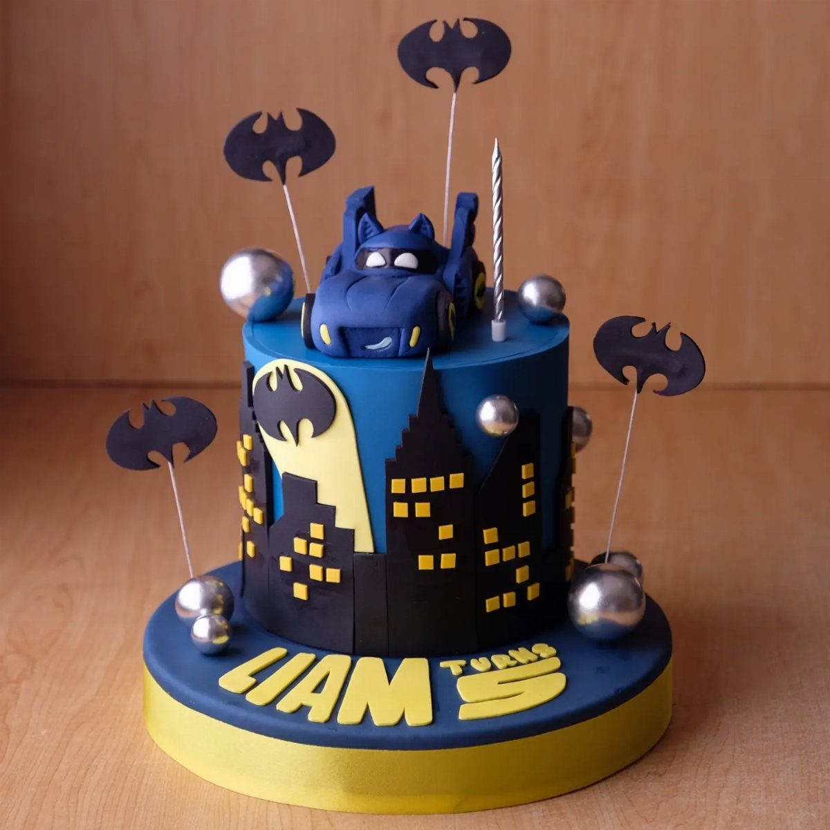 Blue Batman cake with a Batmobile on top and a black city skyline.