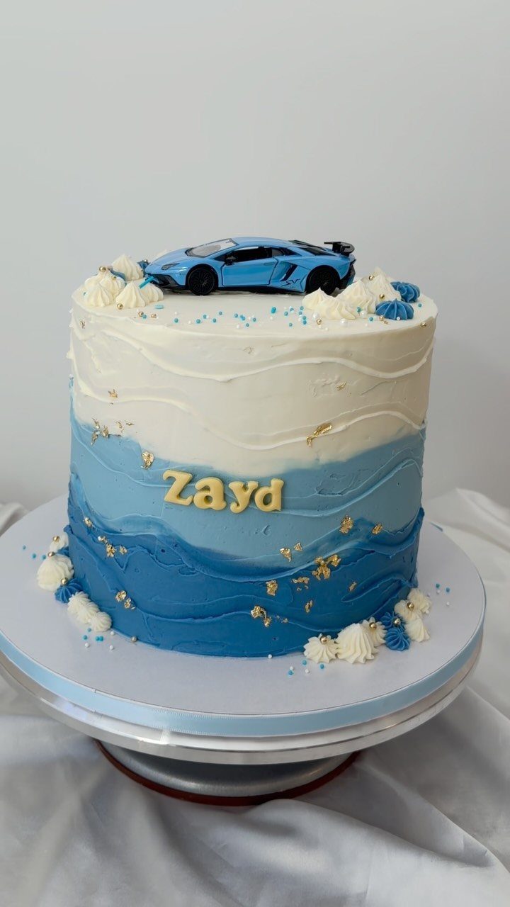 Blue and white ombre cake with a blue toy sports car on top.