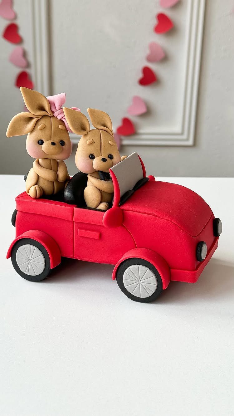 Red car-shaped cake with two cute fondant bunnies sitting in the driver and passenger seats.