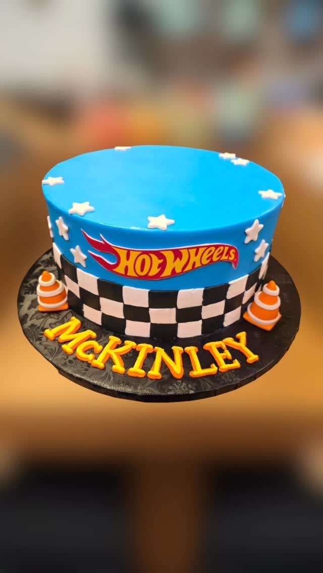 Blue Hot Wheels themed cake with checkered pattern and orange name letters