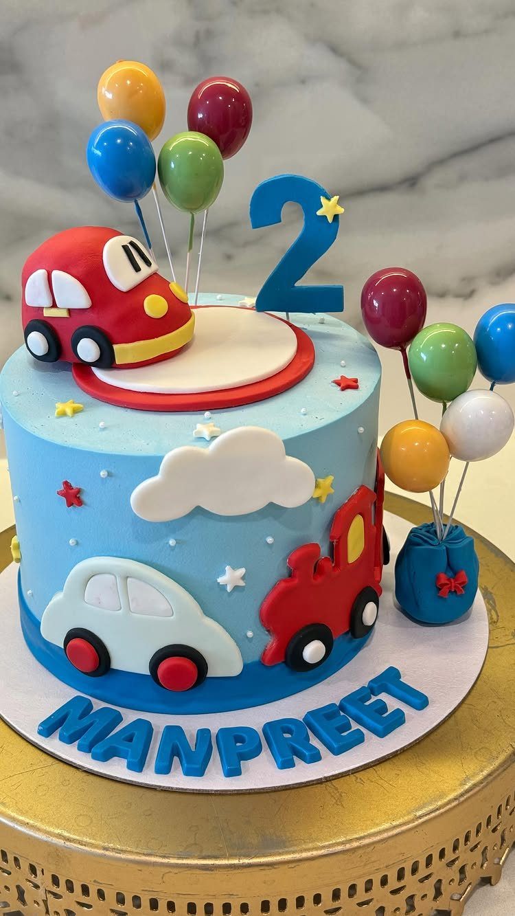 Blue birthday cake with red and white fondant cars, balloons, and a number two.