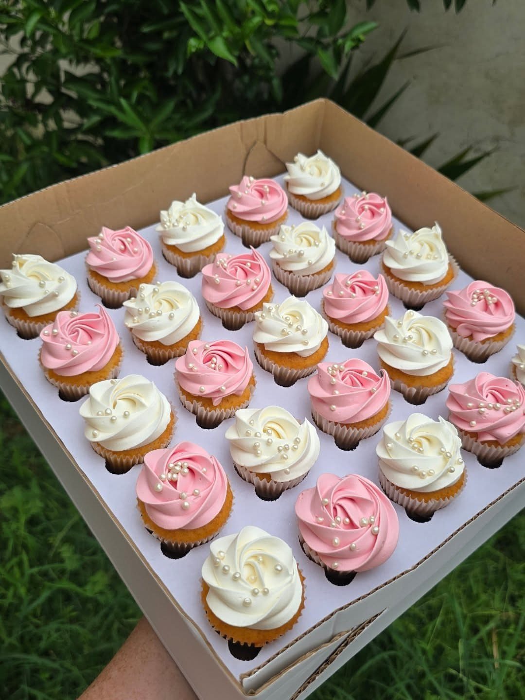 12 Cupcake Cake Ideas for Your Next Celebration 6 Pink and white frosted cupcakes with edible pearls in a cardboard delivery box.