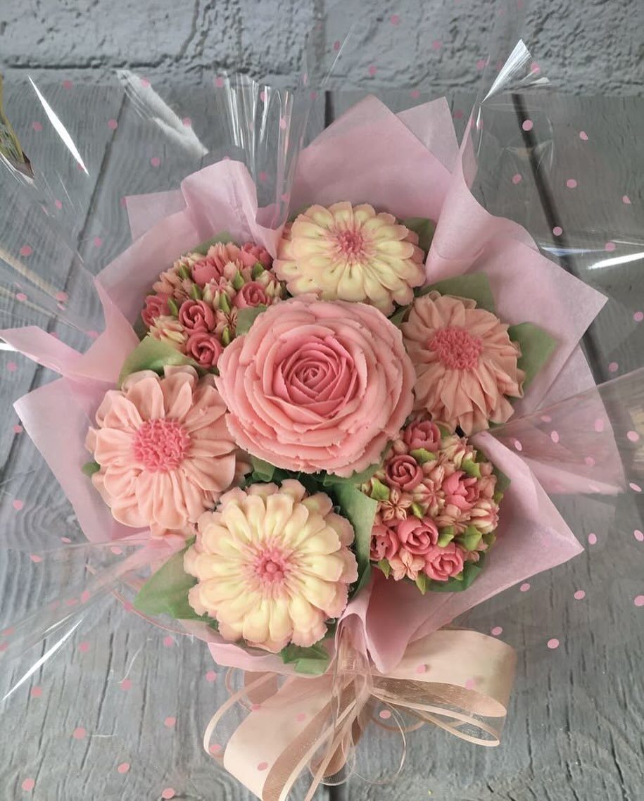 12 Cupcake Cake Ideas for Your Next Celebration 2 Cupcake bouquet with pink and cream frosting flowers wrapped in pink paper and cellophane.