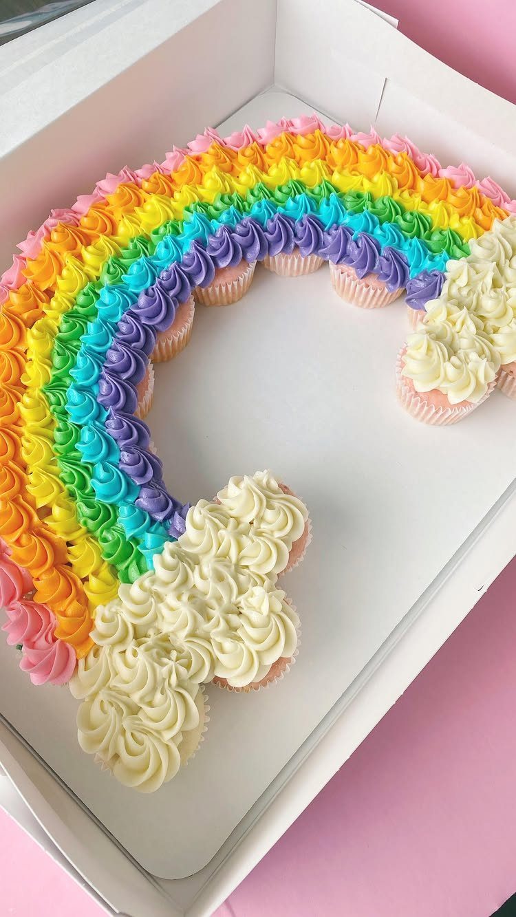 12 Cupcake Cake Ideas for Your Next Celebration 4 Rainbow cupcake cake with colorful frosting arcs and white fluffy frosting clouds.