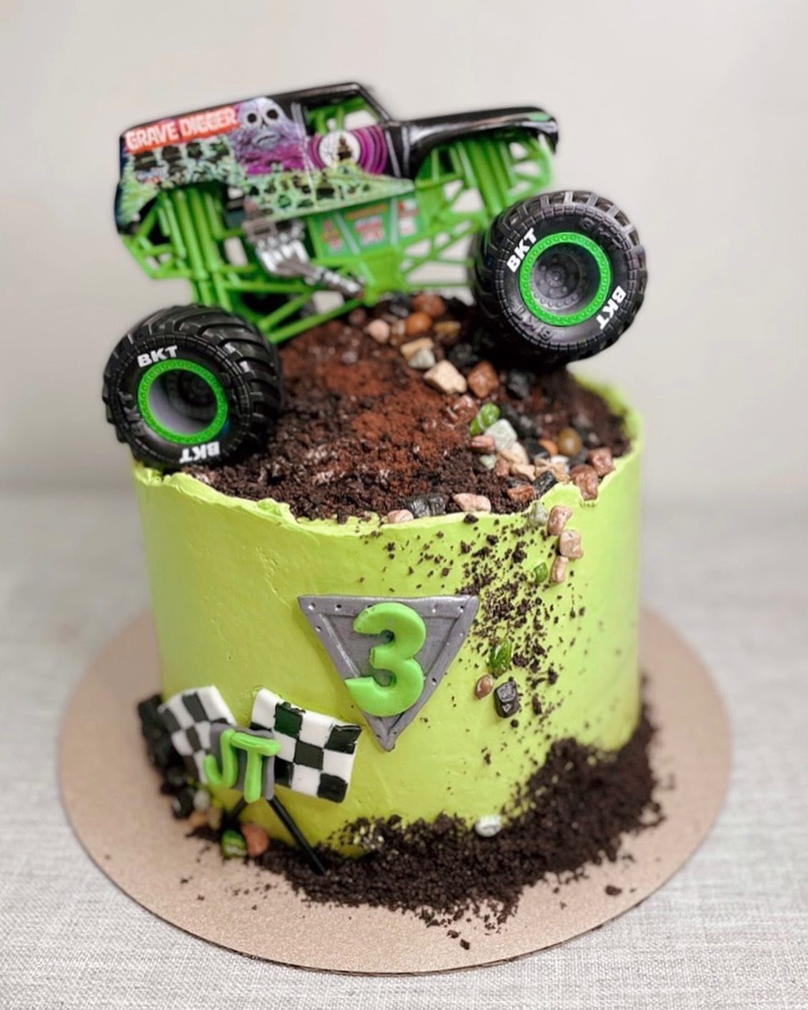 Grave Digger monster truck toy on a lime green cake with chocolate dirt.
