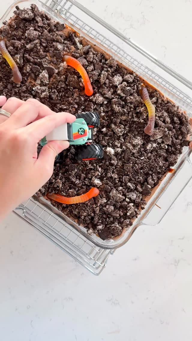 Toy monster truck on a cake topped with crushed Oreo dirt and gummy worms