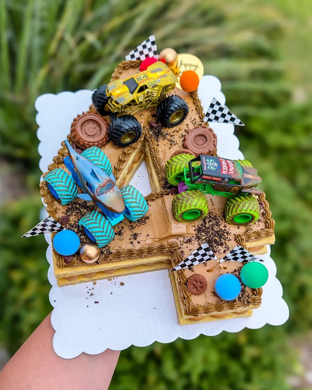 Number four shaped cake with toy monster trucks and crushed Oreo cookie dirt.