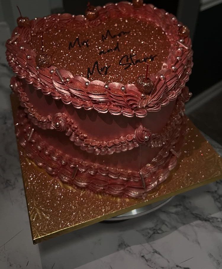 Heart-shaped two-tier rose gold cake with glittery top and piped ruffle frosting details.