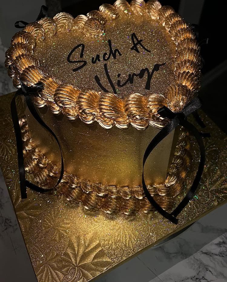 Heart-shaped rose gold cake with black ribbons and Virgo text on top.
