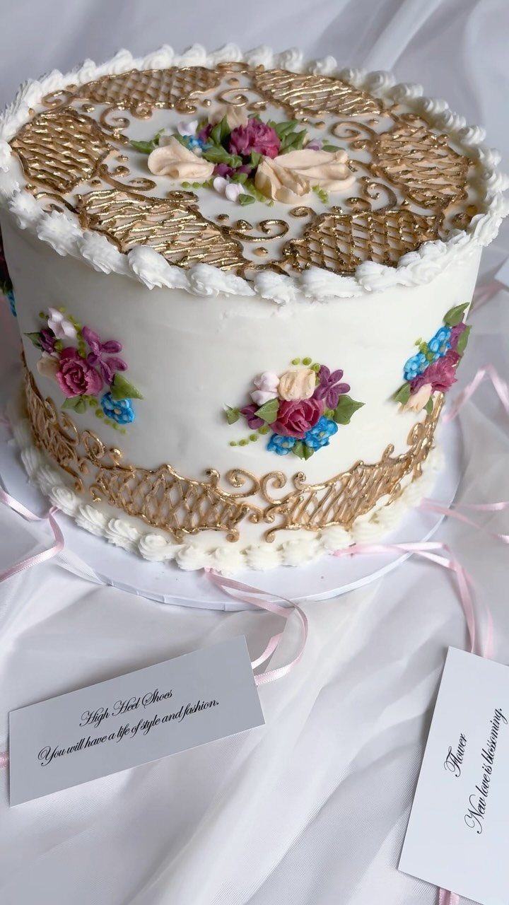 White cake with rose gold metallic lattice patterns and colorful buttercream flowers.