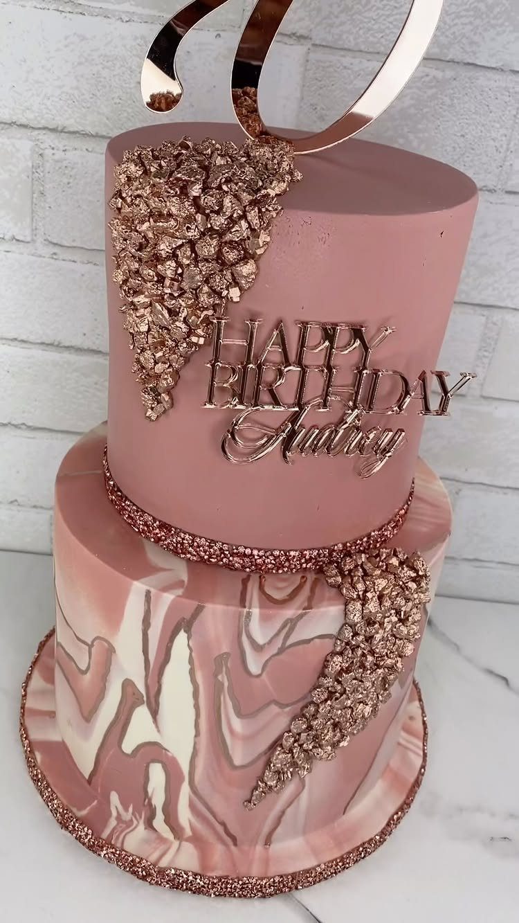 Two-tier rose gold cake with marble frosting, crystals, and a birthday topper.