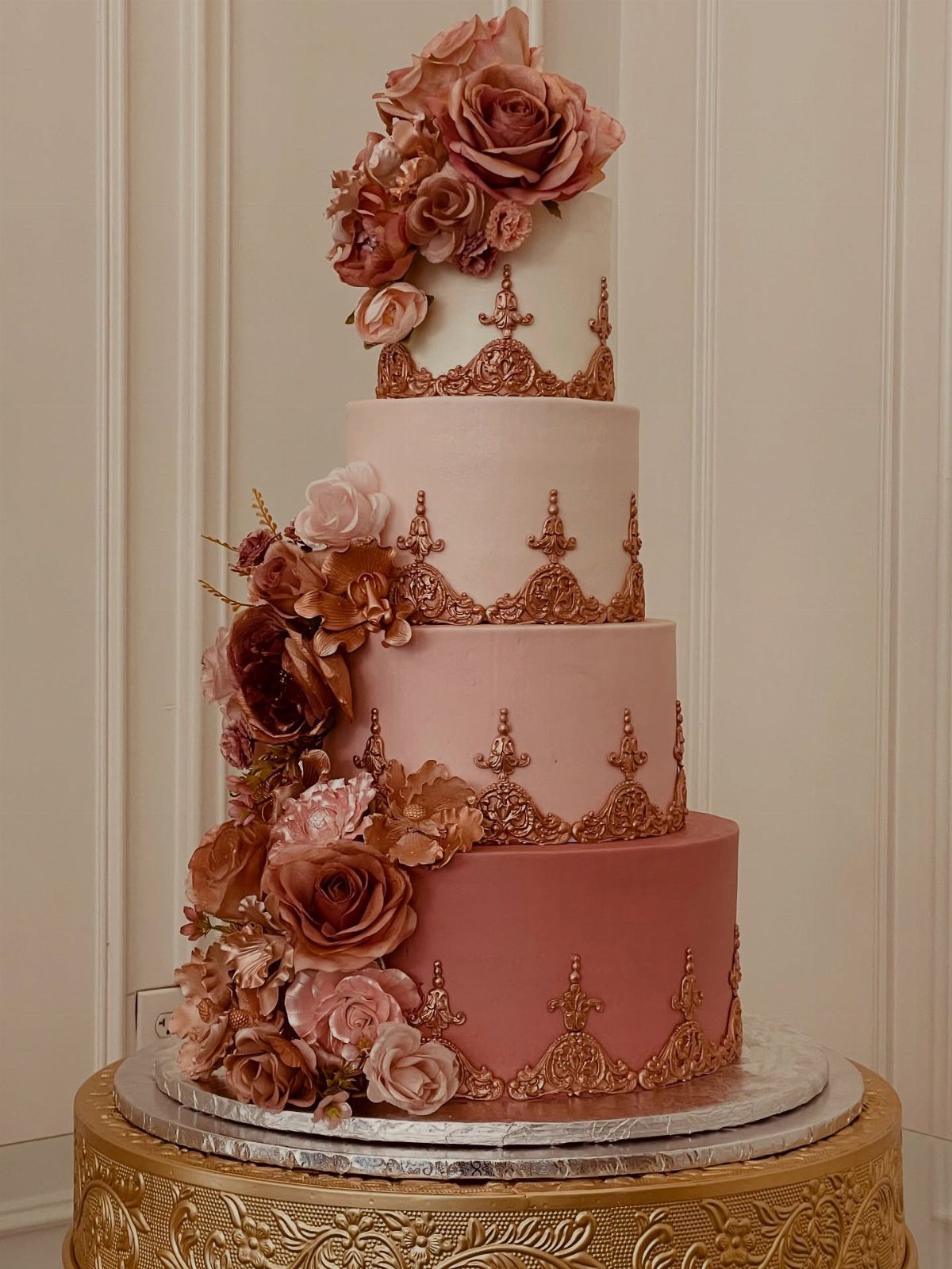 Ombre pink four-tier cake with rose gold sugar flowers and metallic filigree lace.