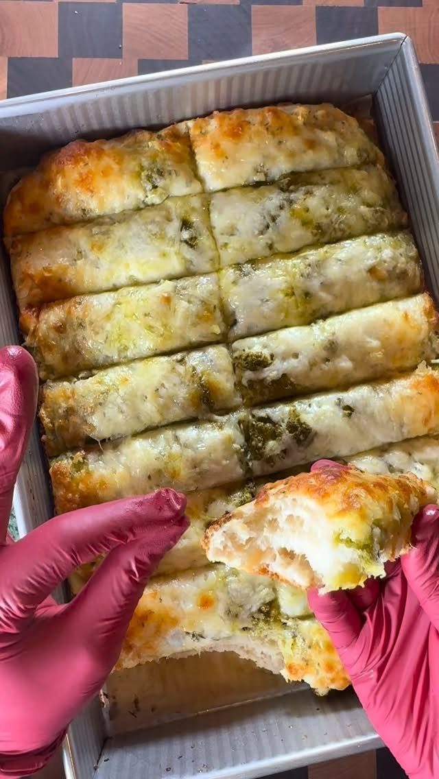 Sourdough Discard Breadsticks with 9 Flavor Ideas 5 Cheesy breadsticks with herb filling in a baking pan held by gloved hands.