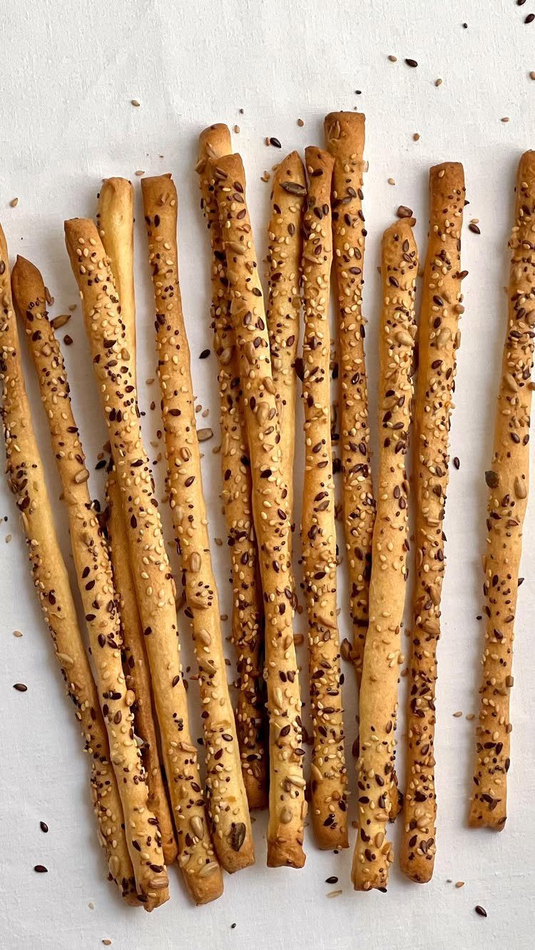 Sourdough Discard Breadsticks with 9 Flavor Ideas 8 Golden-brown seeded breadsticks resting on a white fabric background.
